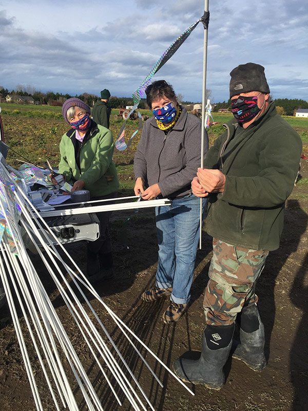 Three people standing in a field with some poles