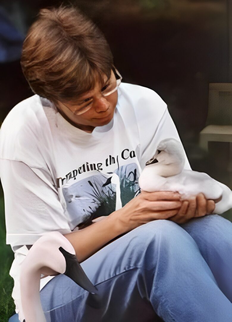 A woman holding a baby bird in her arms.