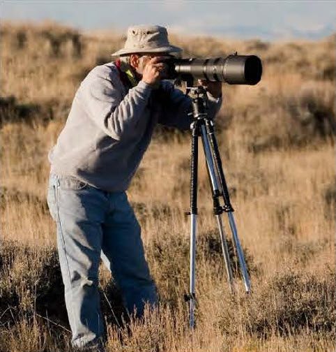 Field photographer with telephoto lens on a tripod