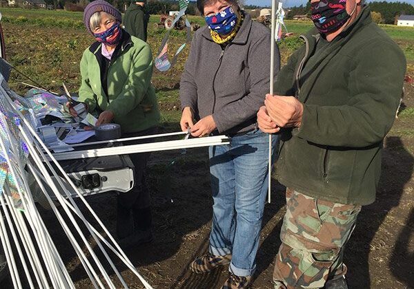 Three people standing in a field with some poles