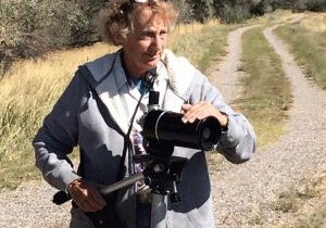 A woman standing on the side of a road holding a camera.