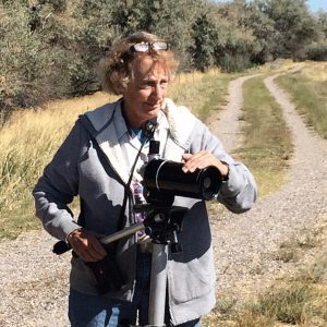 A woman standing on the side of a road holding a camera.